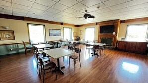 A spacious room with a large wooden table and chairs, a fireplace, and framed artwork on the walls.