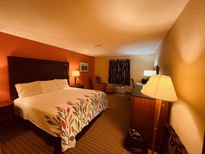 A hotel room with a large bed, a desk with a lamp, a chair, and a waste bin. - Best Value Inn & Suites Parry Sound (Parry Sound)