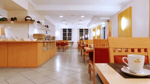 A clean, modern cafe with wooden furniture, a buffet counter, and a coffee station. - Central Hotel Löwen (Feldkirch)