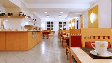 Una cafetería limpia y moderna con mobiliario de madera, una barra de buffet y una estación de café.