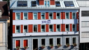Ein Hotel mit roter und weißer Fassade, zahlreichen Fenstern und Blumenkästen im Erdgeschoss.