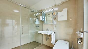 A modern bathroom with a glass shower enclosure, a white sink, and a toilet.