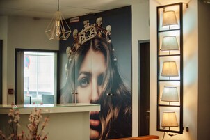 Een receptiegedeelte met een glazen balie, een decoratieve kroon aan de muur en een aantal wandlampen.