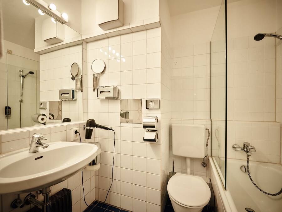Un baño con lavamanos, espejo, inodoro y ducha.