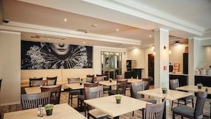 Un restaurante con varias mesas y sillas, un gran mural en la pared y una decoración interior moderna.