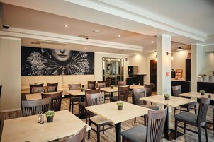 Een restaurant met meerdere tafels en stoelen, een grote muurschildering en een modern interieur.