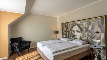 Un dormitorio con una cama, una silla, una lámpara y una obra de arte en la pared.