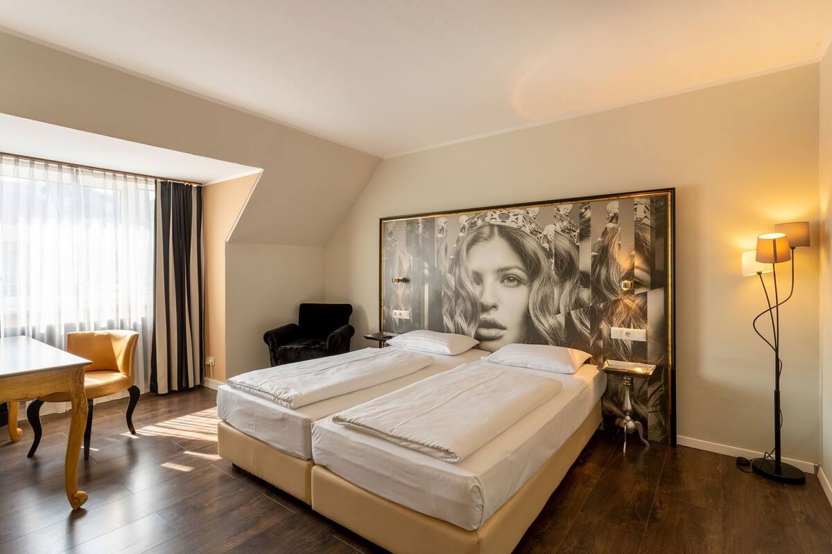 A bedroom with a large bed, a desk, a chair, and a floor lamp.