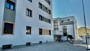A modern hotel with a flat facade, multiple windows, and a gravel driveway. - Arion Hotel Vienna Airport (Schwechat)