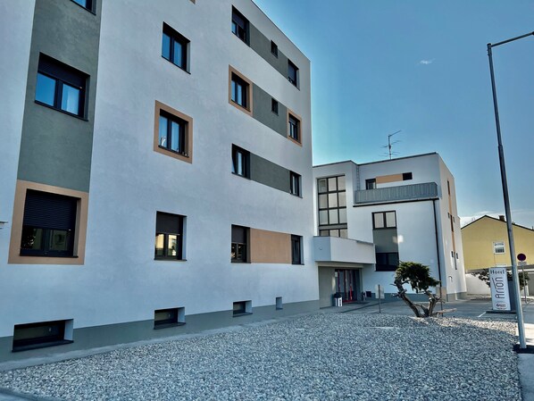 Un hotel moderno con fachada plana, varias ventanas y un camino de acceso de grava.