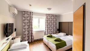 A hotel room with two beds, a television, a window with curtains, and a door. - Arion Hotel Vienna Airport (Schwechat)