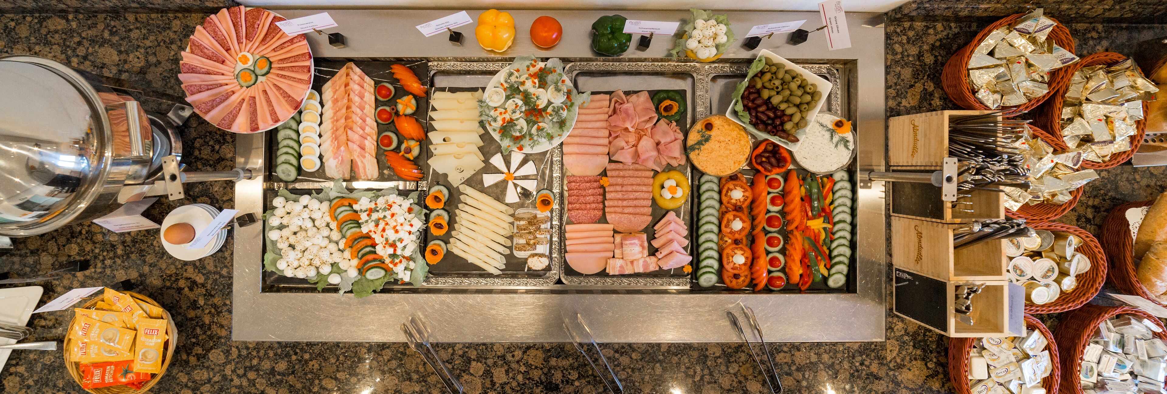 Un bufé con diversos alimentos, incluyendo carnes, quesos y verduras.