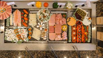 Un bufé con diversos alimentos, incluyendo carnes, quesos y verduras.