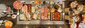 Un bufé con diversos alimentos, incluyendo carnes, quesos y verduras.