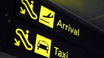 A sign with symbols for arrival, taxi, and luggage.