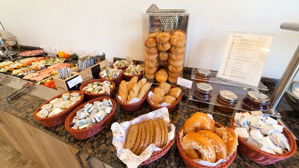A buffet with various food items including breads, pastries, and cheeses. - Arion Hotel Vienna Airport (Schwechat)