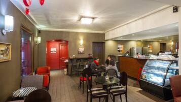 A cozy cafe with tables and chairs, a counter, and a display case with food items.