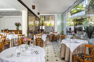 Een restaurant met ronde tafels, stoelen en een betegelde vloer.