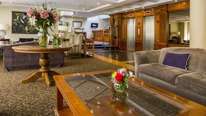 A hotel lobby with a round wooden table, a sofa, and a television on the wall. - Hotel Bonaparte Boutique (Santiago)