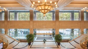 A spacious lobby with a grand chandelier, multiple staircases, and large windows offering views of the parking area. - Hengshan Garden Hotel (Shanghai)