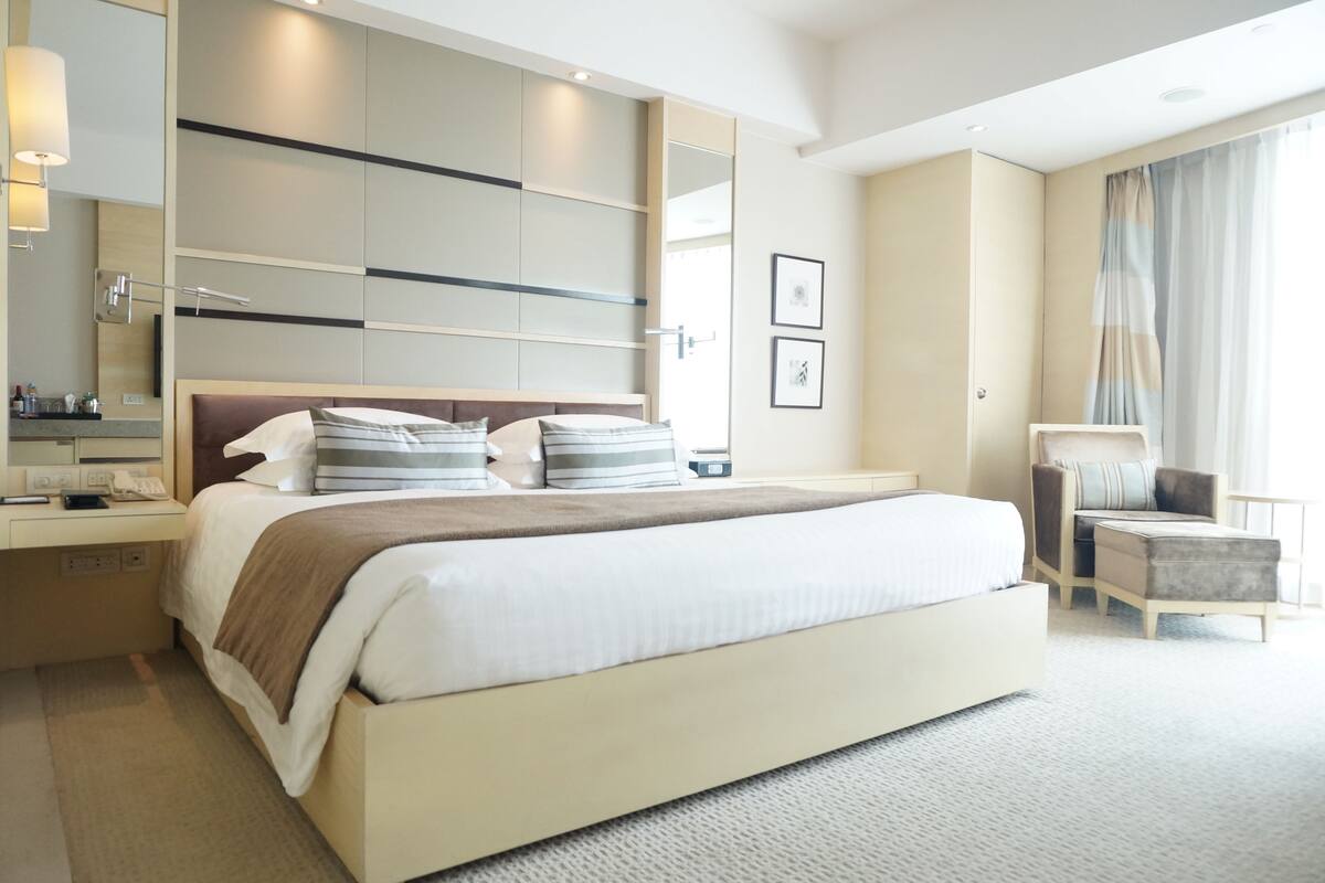 Et moderne hotelværelse med en stor seng, sengeborde, et skrivebord og en stol.
