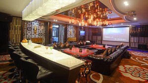 A bar area with a long counter, leather seating, and a projection screen in the background. - Hainan Junhua Haiyi Hotel (Haikou)