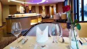 A hotel dining area with a reception desk, tables set for dining, and a large window offering a view. - Hainan Junhua Haiyi Hotel (Haikou)