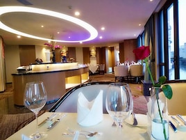 Comedor de hotel con una recepción, mesas dispuestas para comer y un amplio ventanal con vistas.