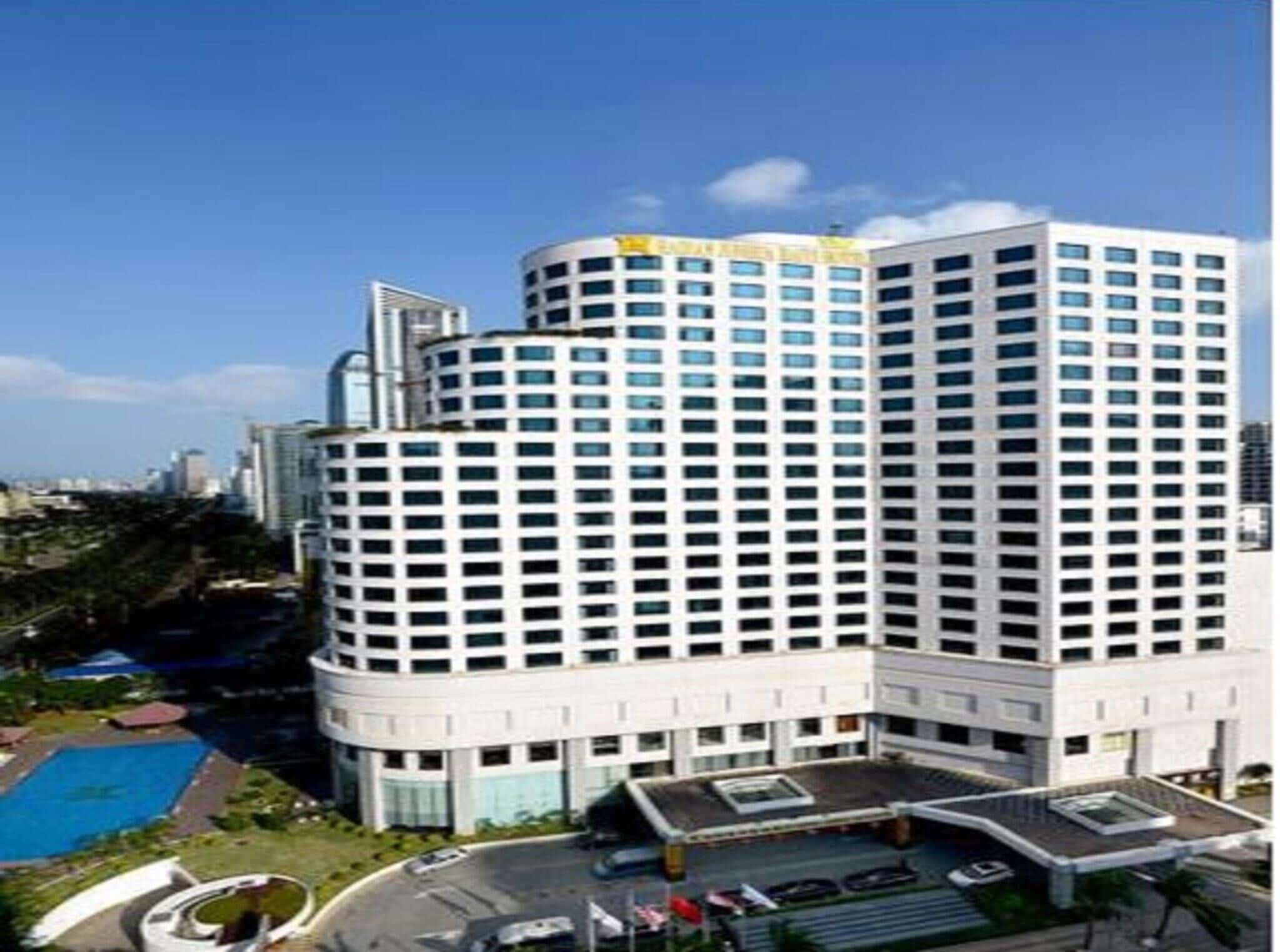 A modern hotel with a curved facade, multiple floors, and a rooftop pool area.
