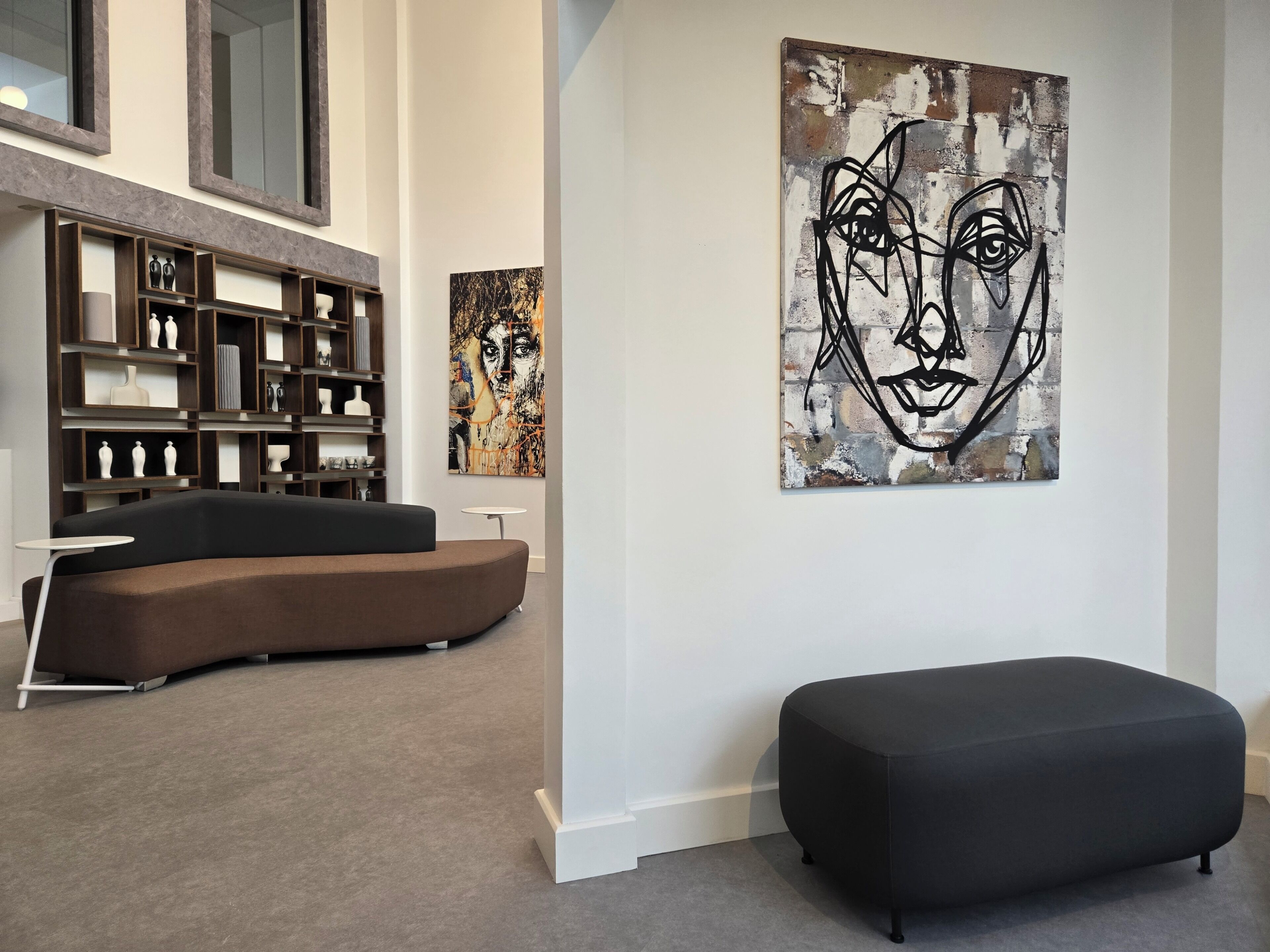 A modern interior with a sofa, a small round table, and a large abstract painting on the wall.