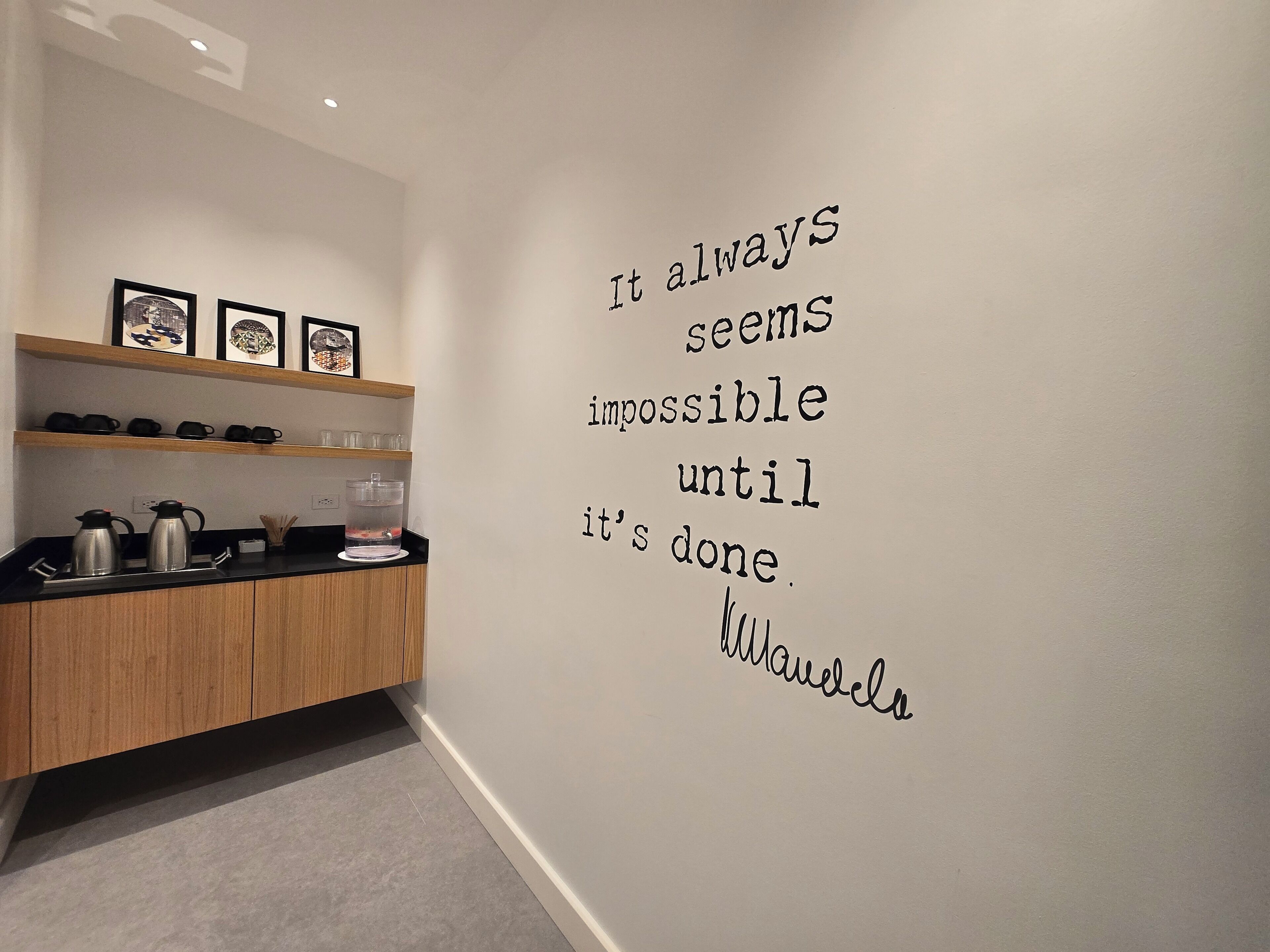A modern kitchen with wooden cabinets, a countertop, and a wall with motivational quote.