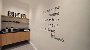 A modern kitchen with wooden cabinets, a countertop, and a wall with motivational quote.