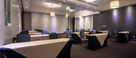 A conference room with tables, chairs, and a large mirror.