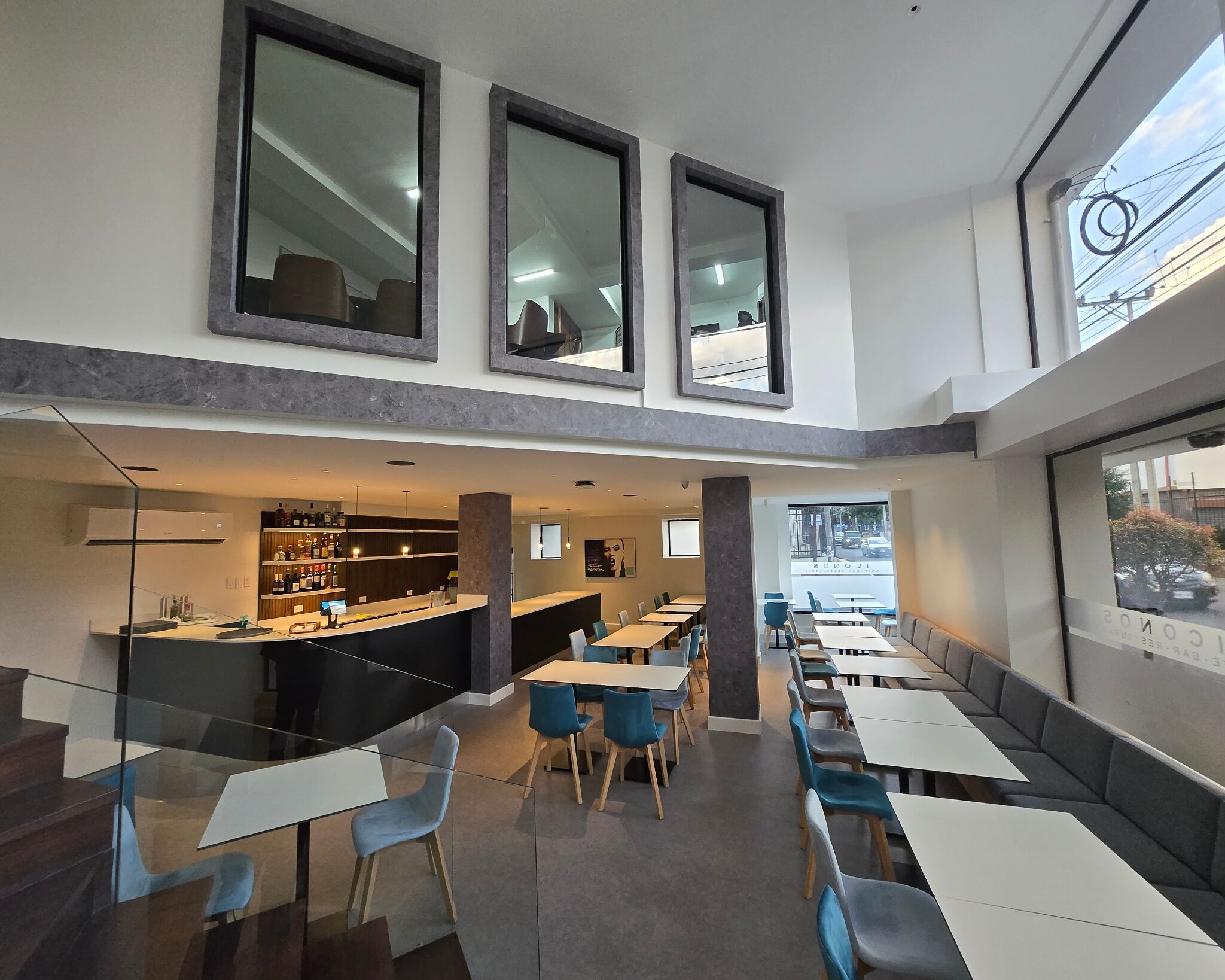 Een modern restaurant met een bar, diverse zitmogelijkheden en grote ramen.