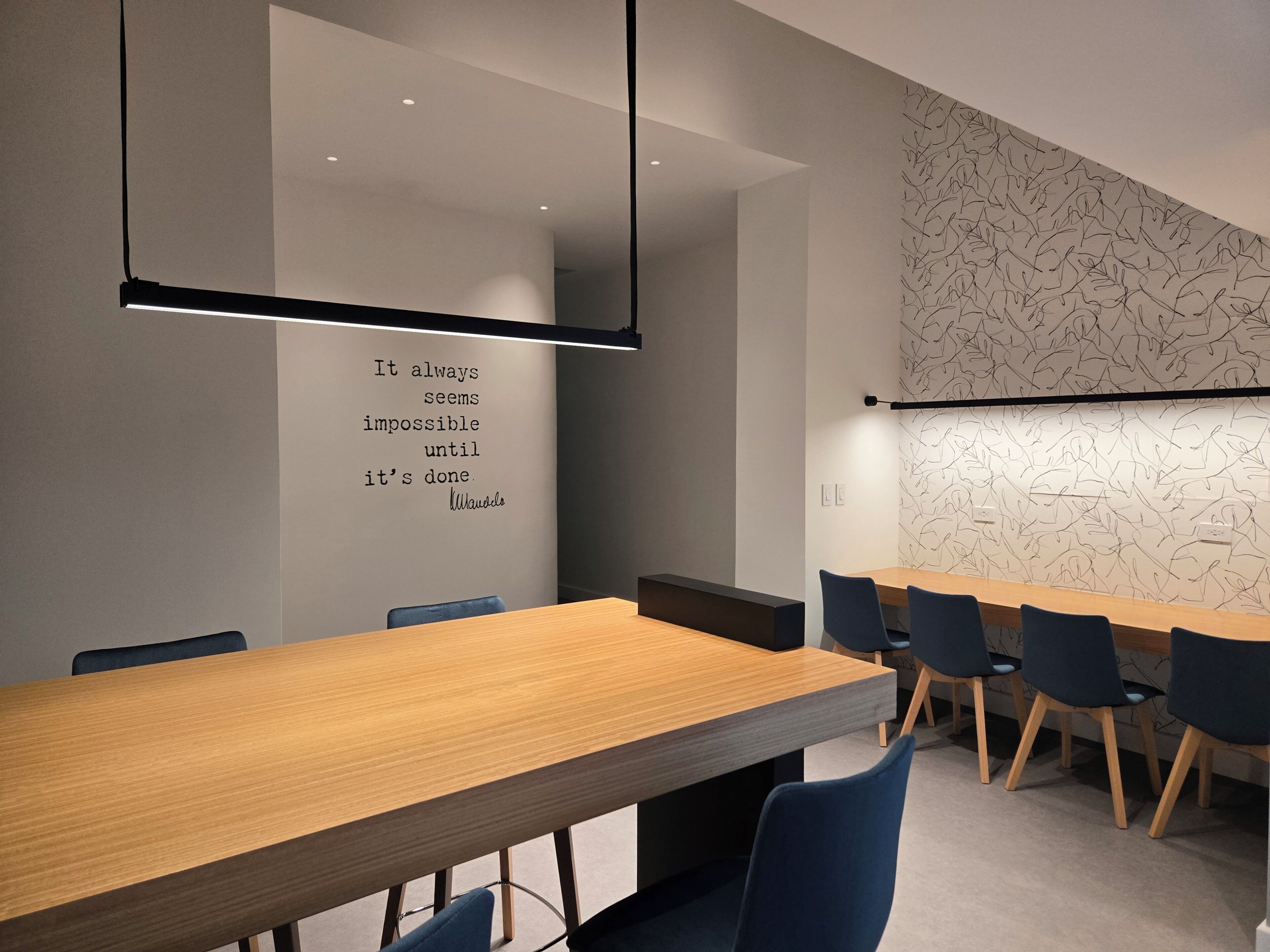 A modern conference room with a long table, chairs, and a motivational quote on the wall.