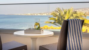 A balcony with a table, chairs, and a view of the sea and palm trees. - Queen's Bay Hotel (Kissonerga)