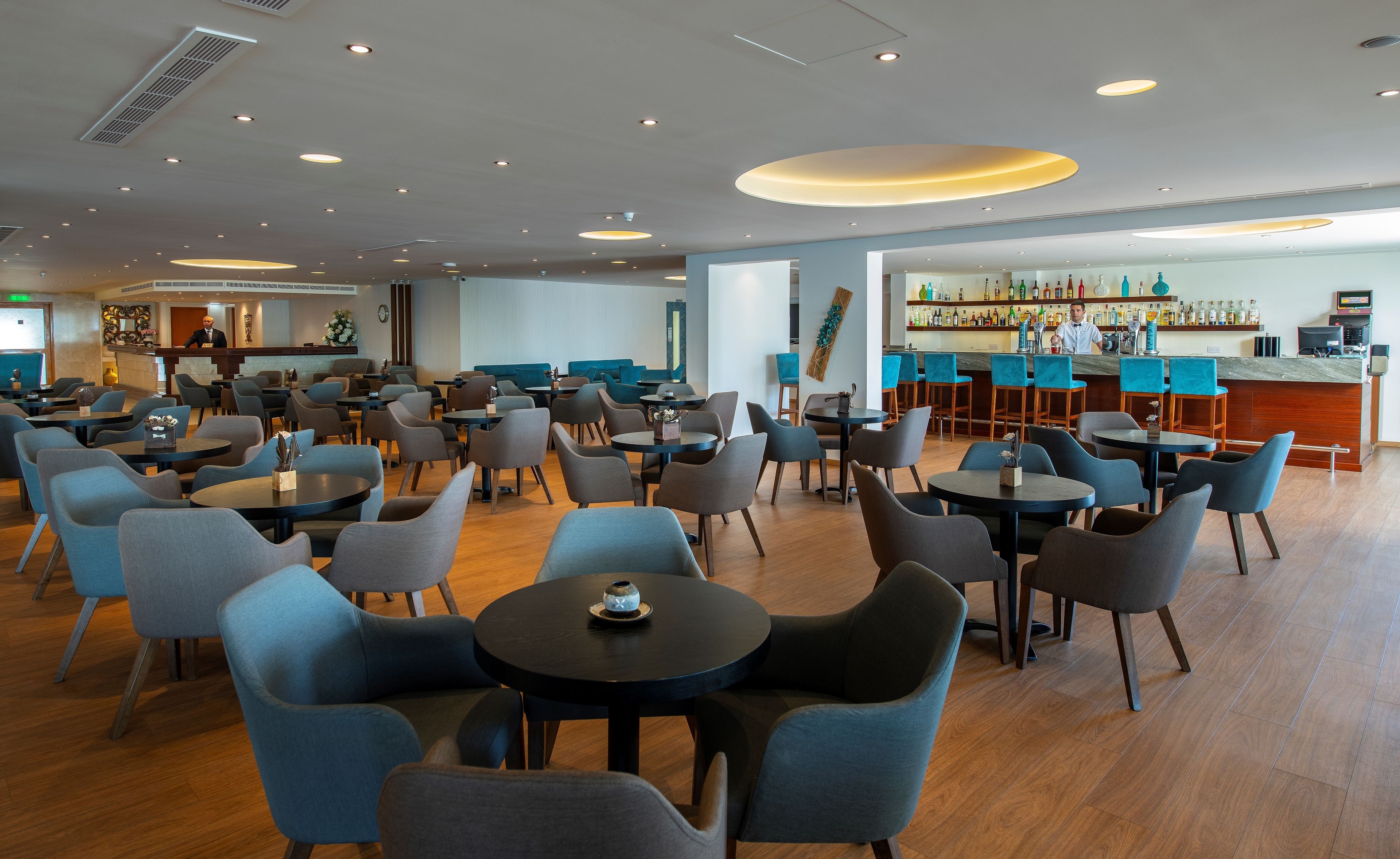 Eine großzügige Hotelhalle mit mehreren Sitzbereichen, einer Bar und einer Rezeption.
