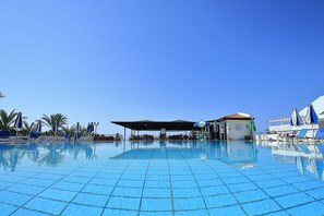 Una piscina al aire libre, sillones reclinables de piscina