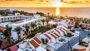 A hotel with multiple buildings, a swimming pool, and a view of the sunset over the ocean. - Helios Bay Hotel Apartments (Chlorakas)