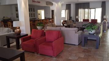 A spacious lobby with a 24hr bar, comfortable seating areas, and a dining space.