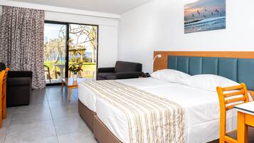 Une chambre d’hôtel avec un lit, un bureau, une chaise, un canapé, une vue sur l’extérieur et un tableau au mur.