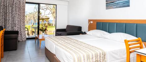 Ett hotellrum med en säng, ett skrivbord, en stol, en soffa, utsikt över omgivningarna och en tavla på väggen.