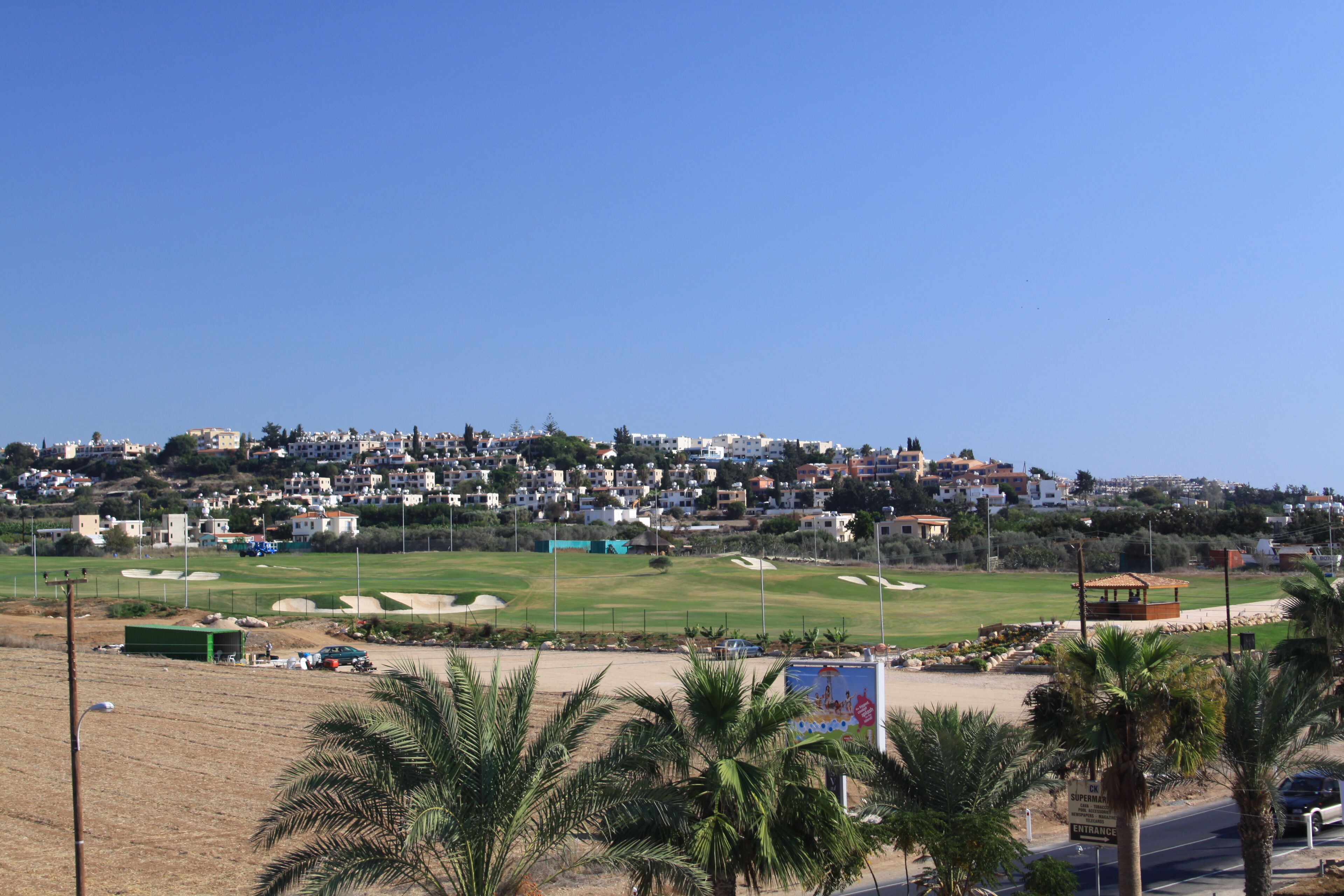 A coastal town with a golf course, palm trees, and residential buildings.