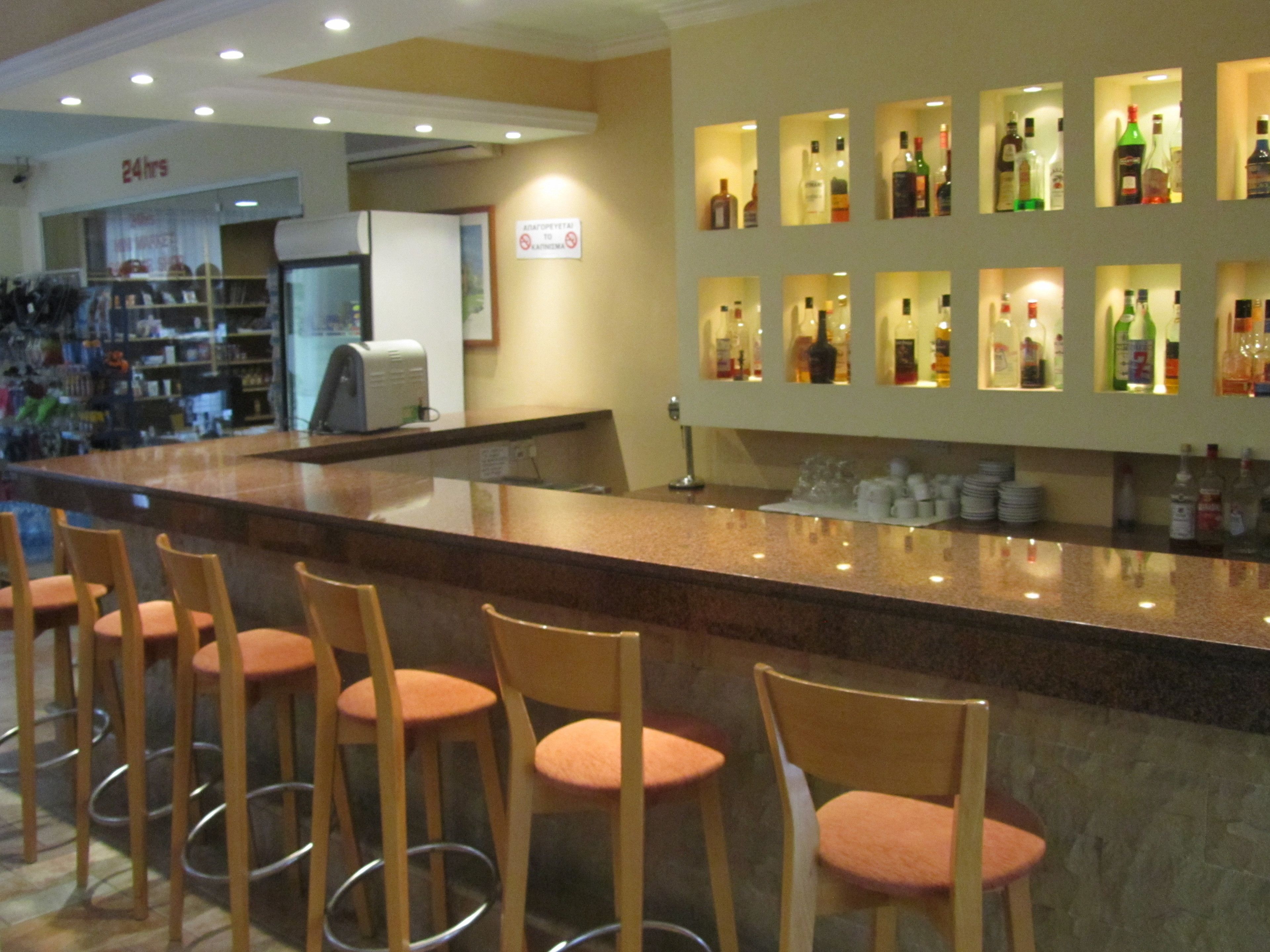 Eine Bar mit Theke, Hockern und einer Wand voller Flaschen.