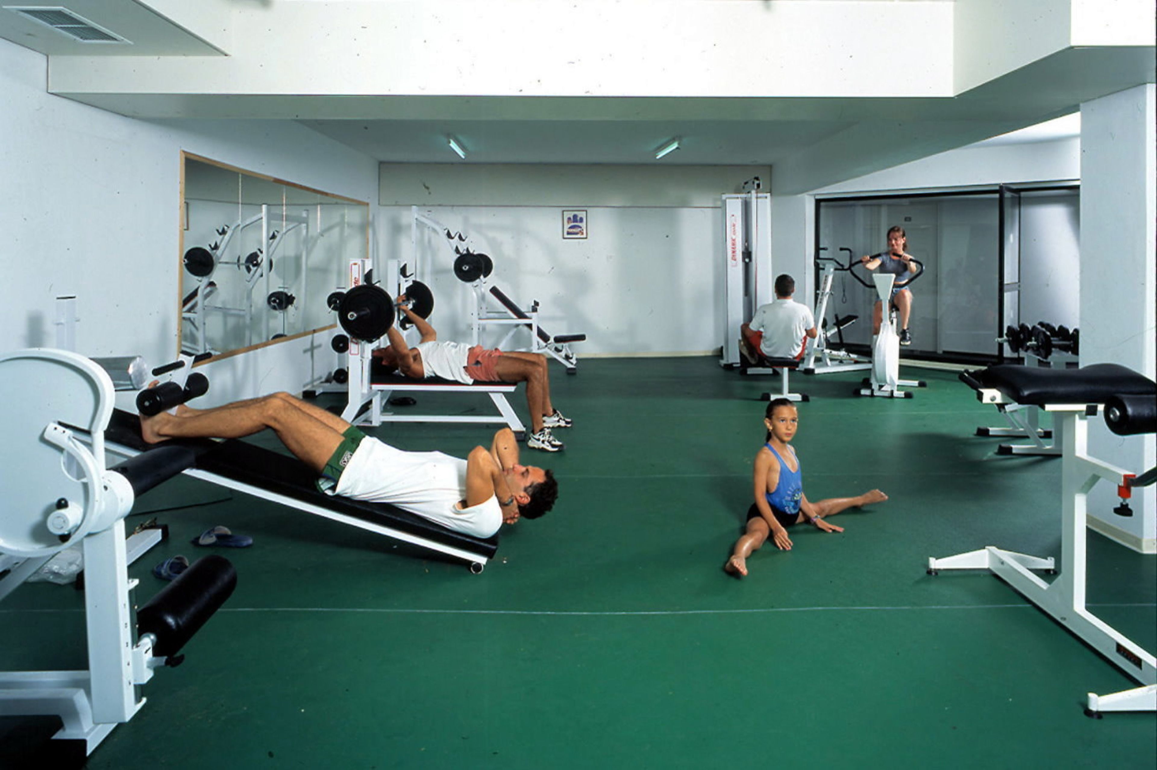 Un gimnasio con diversos equipos de ejercicio, incluyendo cintas de correr y máquinas de pesas.