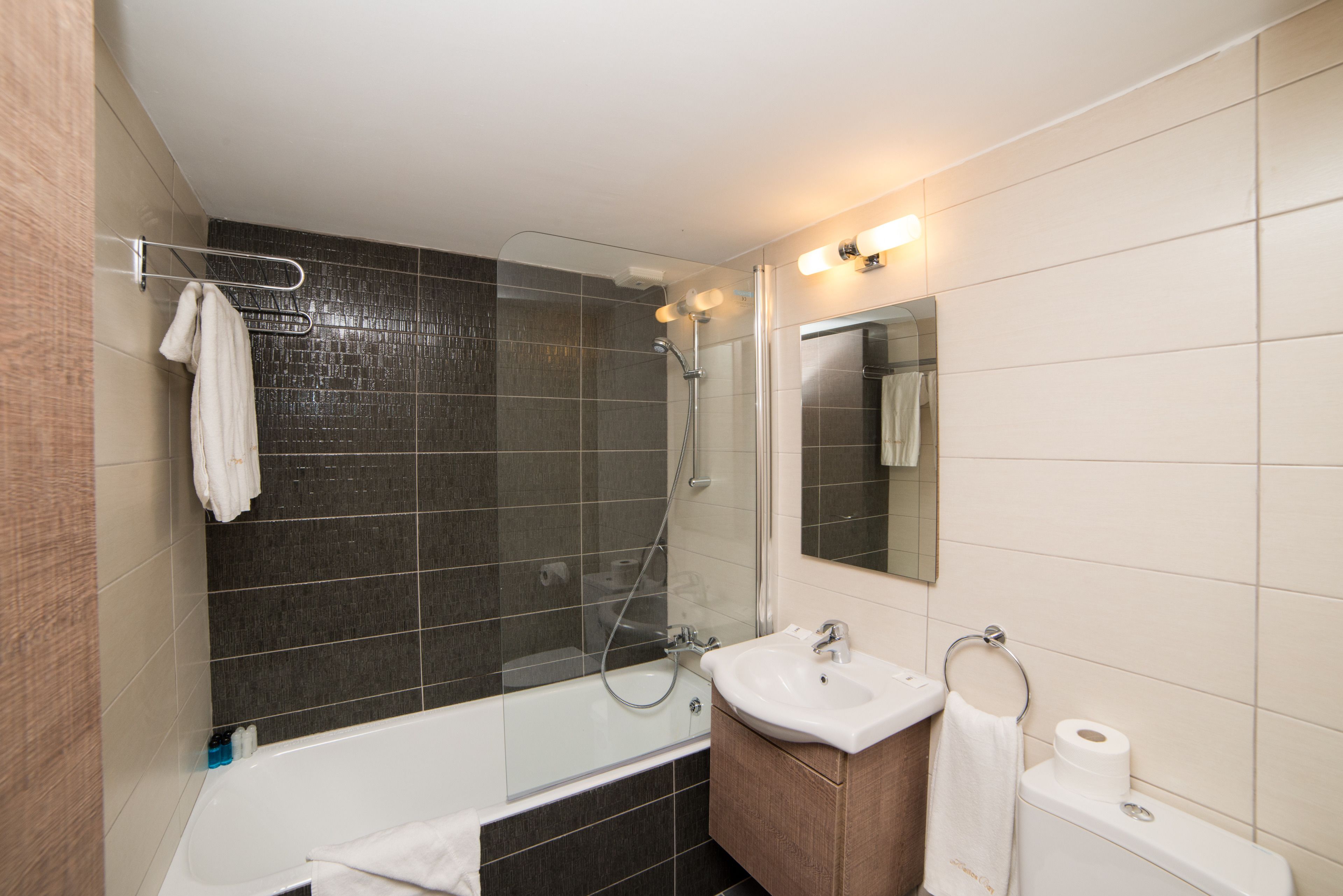A modern bathroom with a glass-enclosed shower, a white sink, and a mirror above the sink.