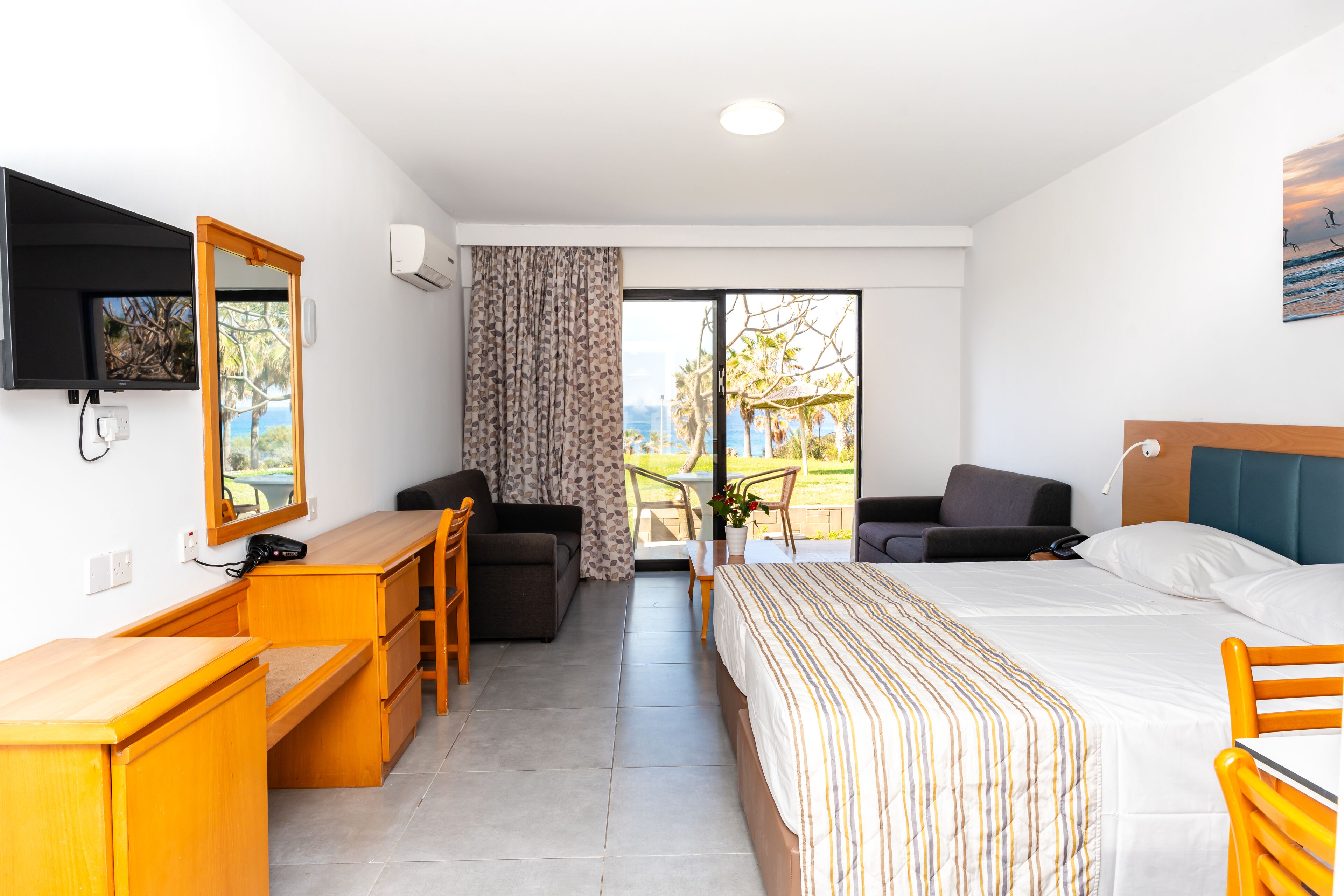 A hotel room with a bed, desk, and seating area.