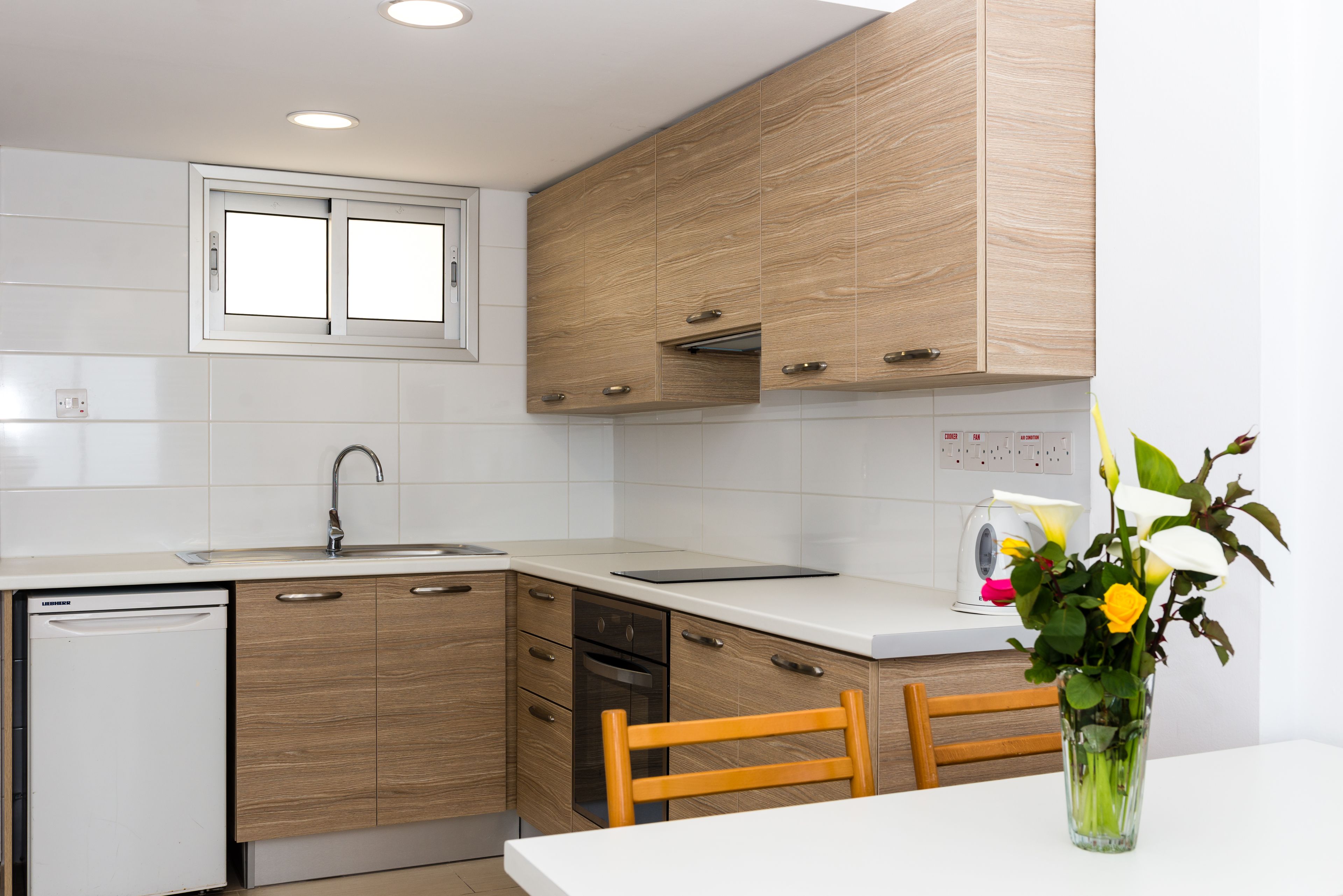 A modern kitchen with wooden cabinets, a dishwasher, a sink, and a window above the countertop.