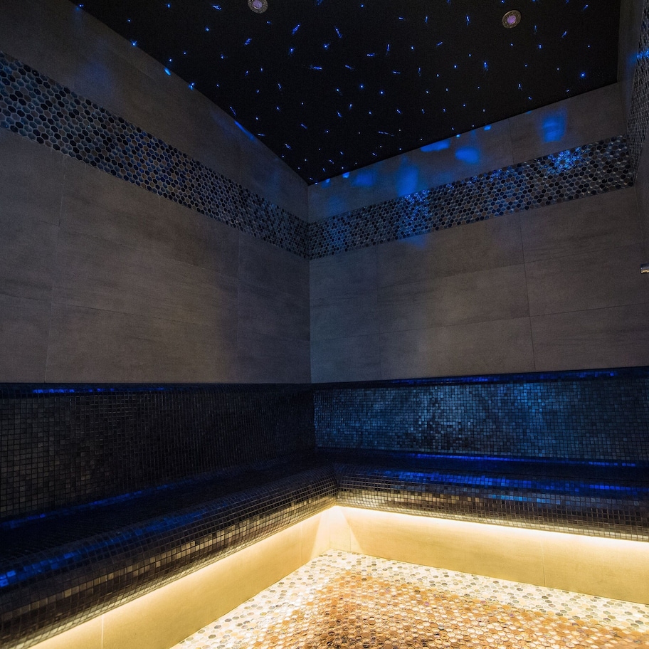 A modern bathroom with a starry ceiling, mosaic tile walls, and a heated floor.