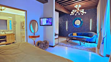 A modern hotel room with a bed, a television, a sofa, and a mirror.
